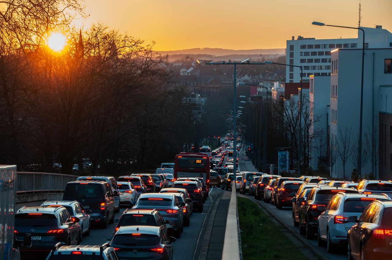 A busy city street jammed with cars and a bus during sunset, capturing urban life and rush hour traffic.